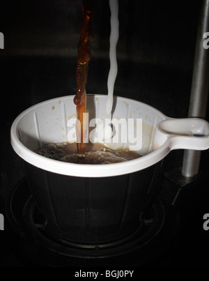 Tasse à café en plastique est déposée dans une machine à café automatique. Banque D'Images