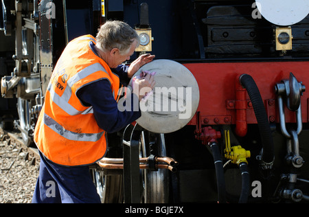 Passionné de trains à vapeur d'époque tampon de nettoyage sur le moteur à une porte-ouverte à Eastleigh Hampshire Travaux Ferroviaires UK Banque D'Images