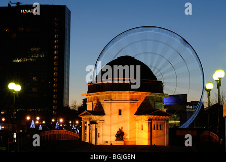 La grande roue en Centennary Square, Birmingham, qui donne le plaisir des manèges, vu avec le Temple de la mémoire, le premier plan, au crépuscule. Banque D'Images