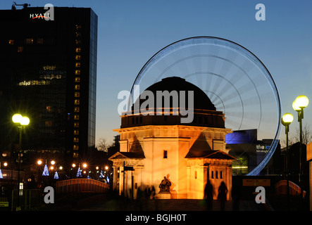 La grande roue en Centennary Square, Birmingham, qui donne le plaisir des manèges, vu avec le Temple de la mémoire, le premier plan, au crépuscule. Banque D'Images