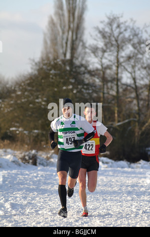 Les hommes s'exécutant en course cross-country dans la neige, Leamington Spa, Angleterre, RU Banque D'Images