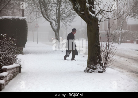 Un homme âgé dans la neige des luttes avec les sacs de Redditch, Worcestershire, Royaume-Uni Banque D'Images