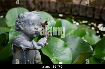 Sculpture d'un garçon - ou putto - étranglant un serpent dans un étang dans un jardin d'Amsterdam, ouverte au public le jour jardin ouvert Banque D'Images