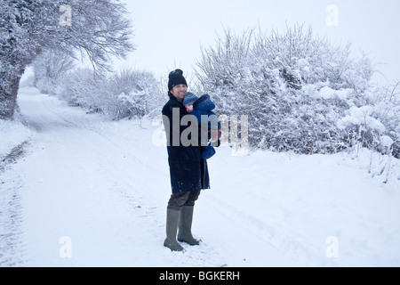 Père et bébé garçon dans la neige, Hampshire, England.dom Banque D'Images