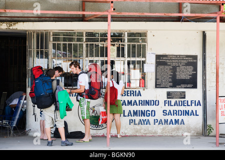 Un groupe de backpackers d'acheter un ticket de bus pour les plages de Guanacaste à partir de la station au Liberia, Costa Rica Banque D'Images