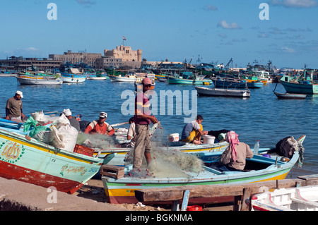 La réparation des filets de pêcheurs sur leurs bateaux de pêche dans le port d'Alexandrie, Egypte. Banque D'Images