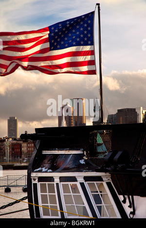 American flag flying à partir de la poupe de l'USS Constitution avec les bâtiments du centre-ville de Boston, Massachusetts USA au-delà Banque D'Images