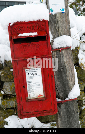 Rusty post box dans un village anglais, couvertes de neige Banque D'Images
