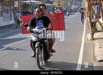 Deux hommes à cheval sur une moto, l'un portant un grand point rouge.Tegallelang Village, Ubud, Bali, Indonésie Banque D'Images