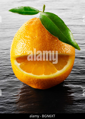 Wole les oranges avec un smiley avec des feuilles sur fond noir Banque D'Images