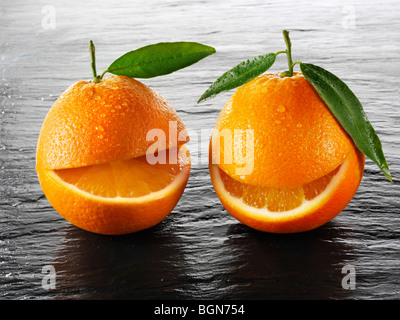 Wole les oranges avec un smiley avec des feuilles sur fond noir Banque D'Images