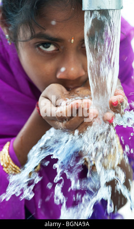 Indian girl boire d'une pompe à eau. L'Inde Banque D'Images