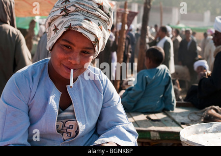 Garçon égyptien fumer une cigarette à un marché aux chameaux dans la vallée du Nil. Banque D'Images