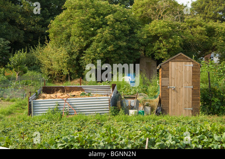 Grand bac à compost fabriqué à partir de métal ondulé sur un allotissement terrain à côté d'un hangar en bois Banque D'Images