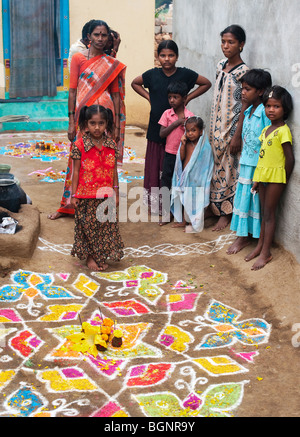 La famille indienne en dehors de leur maison en face d'une conception rangoli dans la rue au cours de la fête hindoue de Sankranti. L'Andhra Pradesh, Inde Banque D'Images