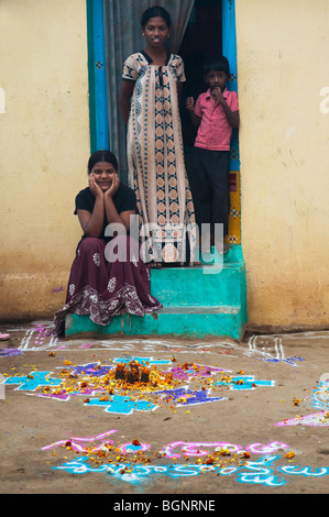 Trois enfants indiens en dehors de leur chambre en face de rangoli sankranti festival dessins dans la rue. Puttaparthi, Andhra Pradesh, Inde Banque D'Images