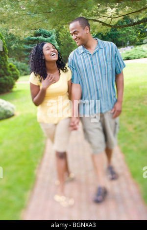 Mid adult man holding mains d'une jeune femme et de la marche dans une pelouse Banque D'Images