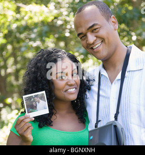 Portrait d'une jeune femme montrant une photo et a Mid adult man standing à côté d'elle Banque D'Images