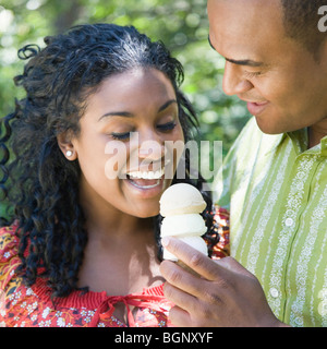 Close-up of a Mid adult man holding une glace et une jeune femme le manger Banque D'Images
