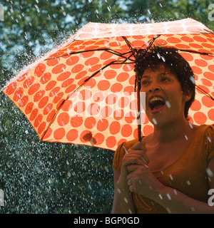 Mature Woman standing sous un parapluie dans la pluie et crier Banque D'Images