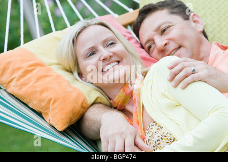 Mid adult woman lying with a young man in a hammock Banque D'Images