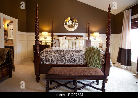 Chambre des maîtres avec lit king size lit à baldaquin recouvert d'une jolie couette et oreillers de pile. Sur le côté des armoires Banque D'Images