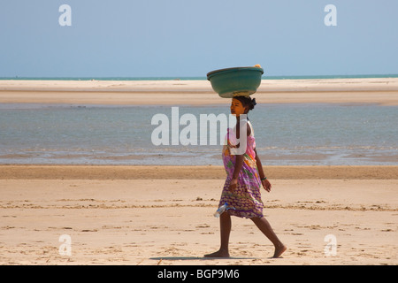 Femme en pâte d'argile en marchant sur la plage de Morondava, Madagascar Banque D'Images