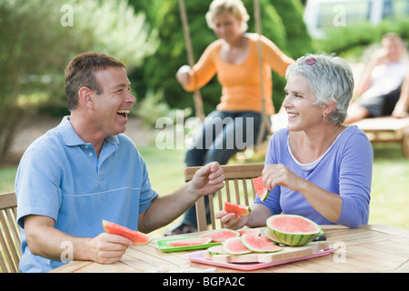 Mature couple eating watermelon tranches dans une pelouse Banque D'Images