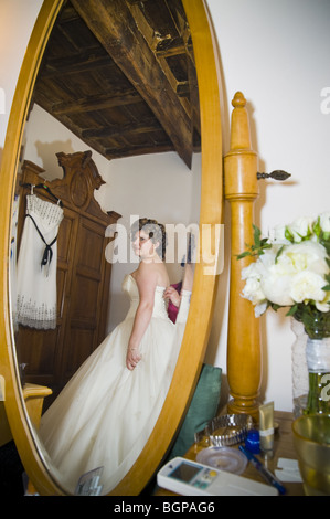 Femme essayant sa robe de mariage devant le miroir Banque D'Images