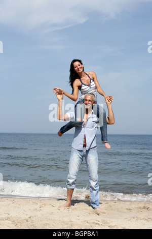 Jolie femme équitation sur les épaules de l'homme sur la plage Banque D'Images