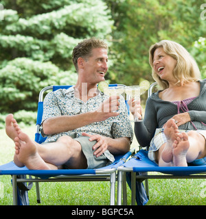 Couple mature sur les chaises longues inclinables et cocktail de Banque D'Images