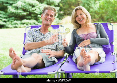 Portrait of a young couple reclining on fauteuils et cocktail de Banque D'Images