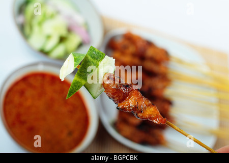 Un stick de poulet satay et tranches de concombre avec la sauce d'arachide, de tranches de concombre et plus le satay dans l'arrière-plan Banque D'Images