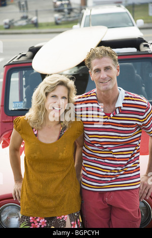 Portrait of a young couple appuyé contre une jeep et smiling Banque D'Images