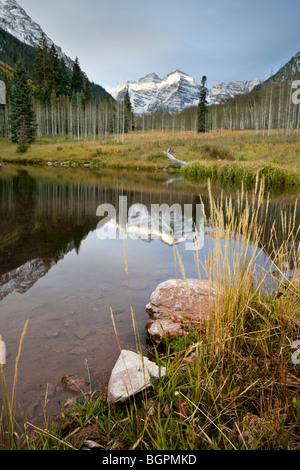 Petit lac avec le reflet de l'Maroon Bells avec les herbes et les rochers au premier plan. Photographie prise au lever du soleil Banque D'Images