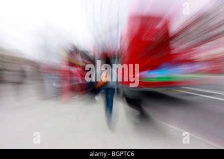 Une jeune femme en jean bleu et portant un grand sac à main tente d'attraper un red London bus à double étage sur le pont de Westminster. Banque D'Images