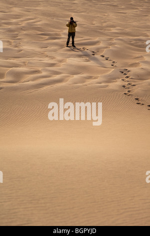 L'homme seul se tenant la photographie des empreintes de pas dans le sable, Great Sand Dunes National Park, Colorado USA Banque D'Images