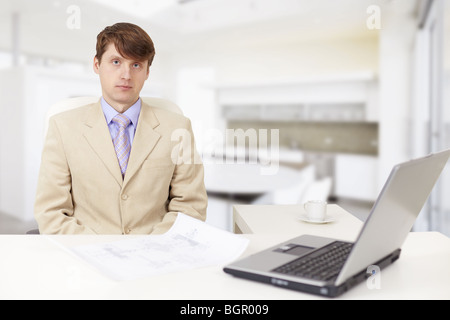 Le jeune homme sérieux sur un lieu de travail avec l'ordinateur portable Banque D'Images