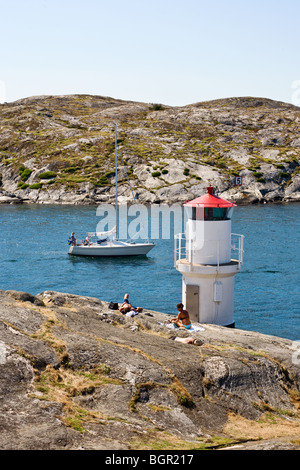 Les personnes qui ont le soleil sur les rochers au phare Banque D'Images