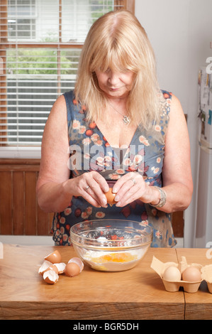 Fissuration des femmes oeufs dans le bol de farine avec les oeufs à côté de shell bowl Banque D'Images