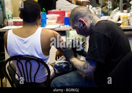 Un homme obtient un tatouage dans un salon de tatouage de la ville de New York. Banque D'Images