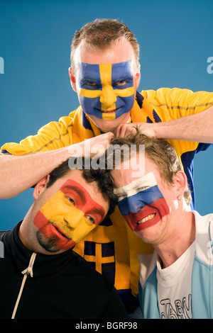 Trois hommes avec différents drapeaux peints sur leurs visages. Banque D'Images