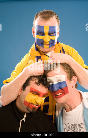 Trois hommes avec différents drapeaux peints sur leurs visages. Banque D'Images