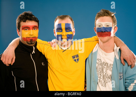 Trois hommes avec différents drapeaux peints sur leurs visages. Banque D'Images