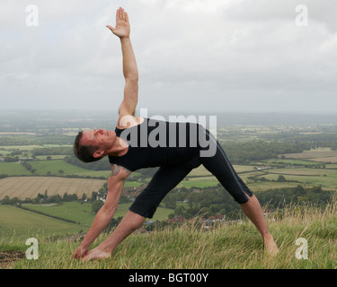 Man doing yoga pose à l'extérieur avec vue sur la campagne anglaise derrière lui Banque D'Images