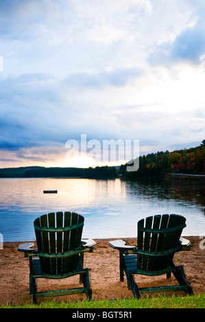 Deux chaises en bois sur la plage du lac de détente au coucher du soleil Banque D'Images
