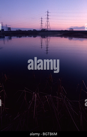 Lea valley Lake avec le soleil se levant au-dessus de lui et d'un pylône d'électricité dans l'arrière-plan Banque D'Images