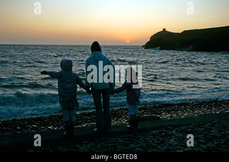 En regardant le coucher de soleil ou lever du soleil à la côte, une mère et ses deux filles. Banque D'Images