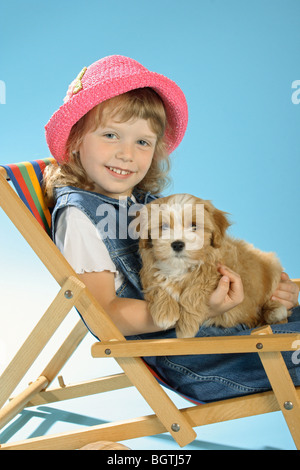 Fille avec chien chiot Bichon Havanais - assis sur un transat Banque D'Images