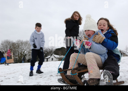 La luge et les enfants jouer dans la neige Bovey Tracey Devon Janvier 2010 Banque D'Images